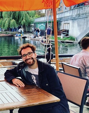 Sebastián Moreno Ramirez seated at an outdoor table with the River Cam and people punting in background