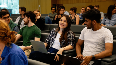 Researchers chatting while sitting with their laptops with other scientists in the Sainsbury Laboratory auditorium