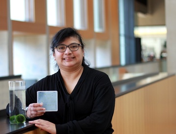 Dr Dora Cano Ramirez pictured with Marimo lake balls and Arabidopsis seedlings with the interior of the SLCU building in the background