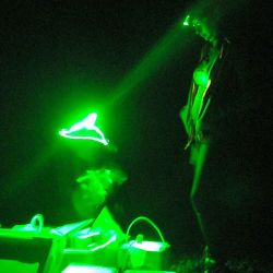 Dora Cano-Ramirez working under green light at night in field experiments in Japan. Dora wears a green headlamp to illuminate the scientific equipment boxes on the ground.