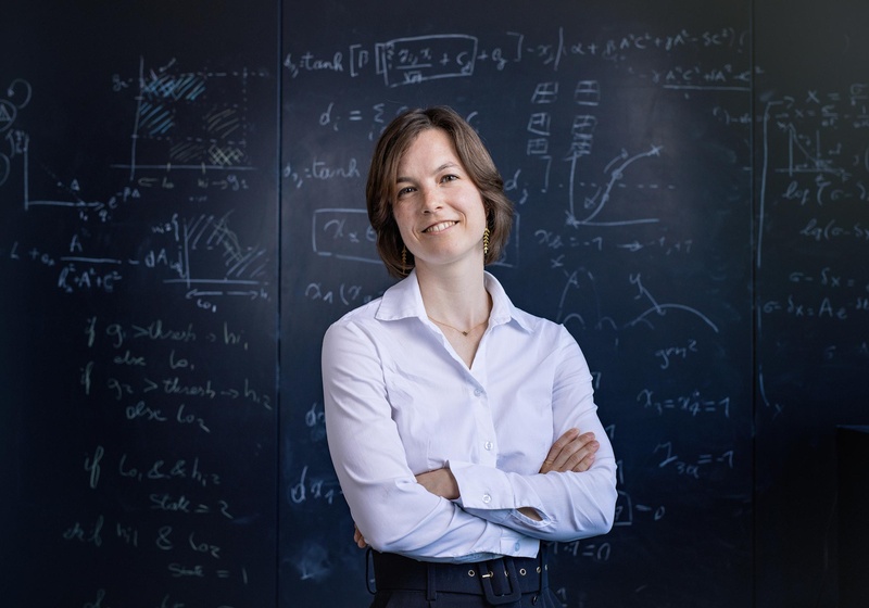 Dr Renske Vroomans standing in front of blackboard with mathematical formulas and graphs written in chalk