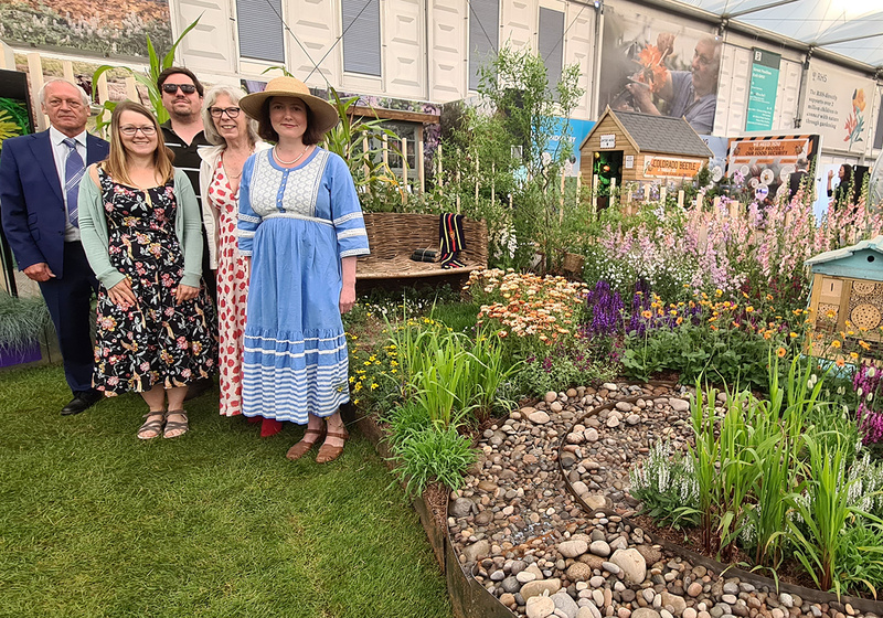 Sadler family members standing in front of The Pollinator Patch garden featuring a stone lined water rill and pollinator friendly plants